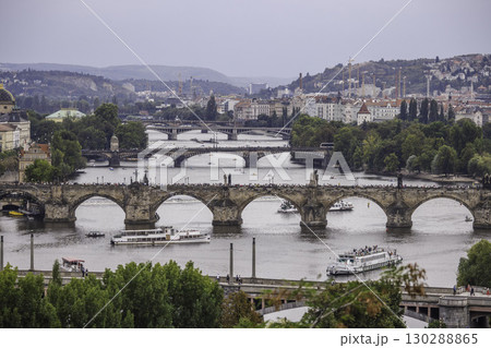 View of Charles Bridge and multiple bridges across the Vltava River in Prague with boats and cityscape in the background 130288865