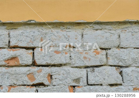 A chipped brick wall. Bricks with fragments of plaster. Textured wallpaper. Concept of building and masonry reconstruction. A chipped brick wall. Bricks with fragments of plaster. Textured wallpaper. Concept of building and masonry reconstruction. 130288956