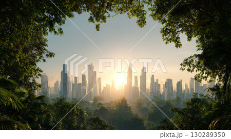 Sunrise over modern city skyline with tall skyscraper buildings surrounded by lush green forest and tree branches framing scene 130289350