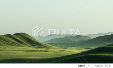 Green rolling hills under soft sunlight with distant mountain range and clear sky creating peaceful natural landscape 130289401
