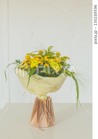 Floral Birthday Gift. Flower bouquet in craft paper bag on white background 130289596