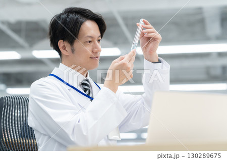 研究所で実験をする白衣の若い男性研究者 研究所で実験をする白衣の若い男性研究者 130289675