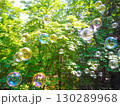 Here's a catchy caption for your image, along with appropriate hashtags: "Floating magic through the green canopy! These iridescent bubbles caught in the sunlight are giving us ultimate carefree vibes 130289968