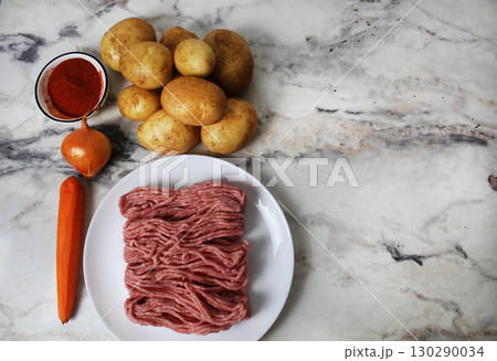 Potatoes, minced meat, paprika, seasoning, onions, carrots on the table. Potato recipe with meatballs cutlets Potatoes, minced meat, paprika, seasoning, onions, carrots on the table. Potato recipe with meatballs cutlets 130290034