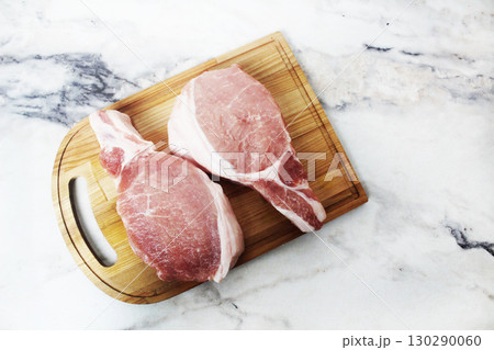 Two raw pork steaks lying on a wooden plank top view Two raw pork steaks lying on a wooden plank top view 130290060