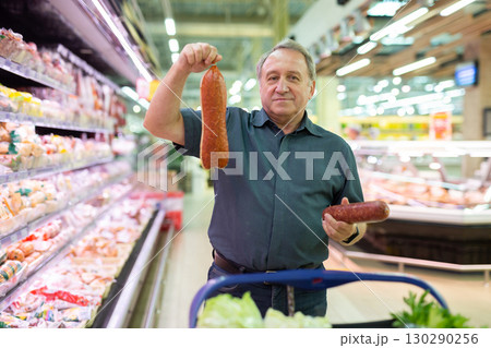 Elderly man chooses sausage in supermarket 130290256