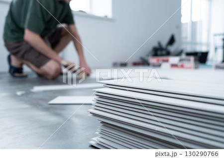 A man lays a quartz laminate on the floor. Renovation, Installation of French herringbone A man lays a quartz laminate on the floor. Renovation, Installation of French herringbone 130290766