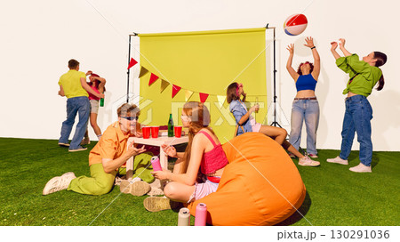 Friends chatting and playing with beach ball under festive banner backdrop Friends chatting and playing with beach ball under festive banner backdrop 130291036