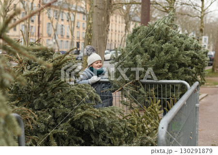 A girl throw away Christmas trees behind the fence 130291879