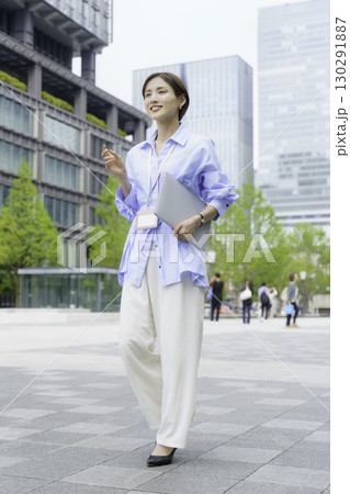 オフィス街でノートパソコンを手にする若いビジネスウーマンのポートレート 縦位置 オフィス街でノートパソコンを手にする若いビジネスウーマンのポートレート 縦位置 130291887