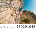 Climber on via ferrata trail, crossing a steep mountain edge 130291946