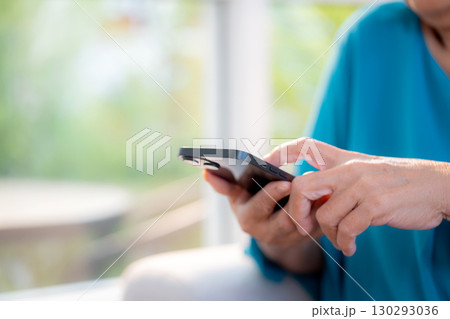 Close up senior woman using on smartphone sitting on sofa in living room at home, digital lifestyle. Close up senior woman using on smartphone sitting on sofa in living room at home, digital lifestyle. 130293036