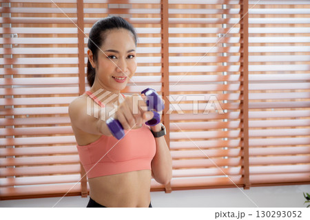 Young asian woman in sportswear workout with dumbbells for strength and strong in living room. 130293052