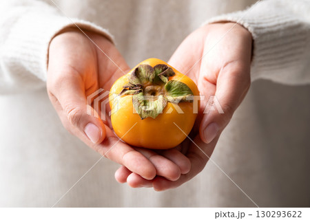 Fresh ripe persimmon holding by woman hand, Autumn sweet fruit 130293622