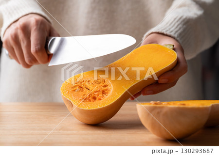 Woman hand holding kitchen knife and cutting butternut squash on wooden board, Homemade cooking Woman hand holding kitchen knife and cutting butternut squash on wooden board, Homemade cooking 130293687