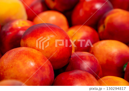 Close-up a lot of fresh red yellow colored peaches on market stall or in groceries shop area. Nectarines background. Fruit food background. Selective focus Close-up a lot of fresh red yellow colored peaches on market stall or in groceries shop area. Nectarines background. Fruit food background. Selective focus 130294817