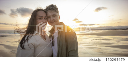 Lesbian couple smiling and enjoying golden sunset on beach Lesbian couple smiling and enjoying golden sunset on beach 130295479