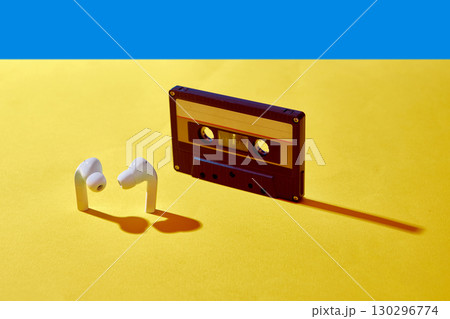 Cassette tape and modern earbuds on bright yellow background 130296774
