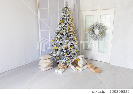 Christmas tree decorated with garlands and gifts in the interior of a white room for the new year 130296823
