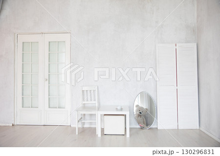 Chair, table and mirror in the interior of an white room with a door 130296831