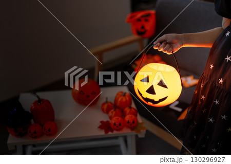 Halloween fun. Child holding a glowing pumpkin while surrounded by festive decorations. 130296927
