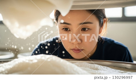 Young Asian woman looking into washing machine drum in laundry room Young Asian woman looking into washing machine drum in laundry room 130296997