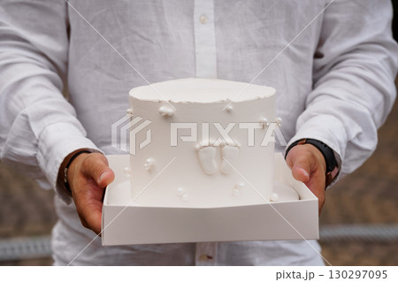 Loving Father Holding Baby Footprint Cake: Celebration of New Birth, White Frosting, Textured Linen Shirt, Outdoors, Parenthood Theme. 130297095