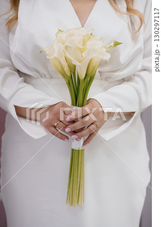 Elegant Bride Holding Cream Calla Lily Bouquet: Wedding, White Dress, Romance, Luxury, Floristry, Close-Up, Celebration, Minimalist Style. Elegant Bride Holding Cream Calla Lily Bouquet: Wedding, White Dress, Romance, Luxury, Floristry, Close-Up, Celebration, Minimalist Style. 130297117