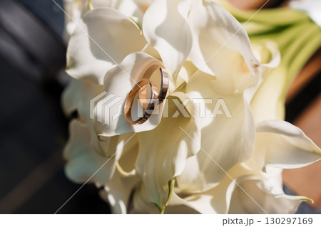 Elegant Wedding Rings Nestled in White Calla Lilies Bouquet, Rose Gold Bands, Symbolic Love and Commitment, Soft Focus Floral Still Life. Elegant Wedding Rings Nestled in White Calla Lilies Bouquet, Rose Gold Bands, Symbolic Love and Commitment, Soft Focus Floral Still Life. 130297169