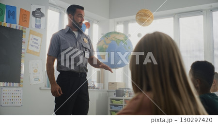 Male Policeman Giving Lecture to Curious Primary School Students About Safety Rules 130297420