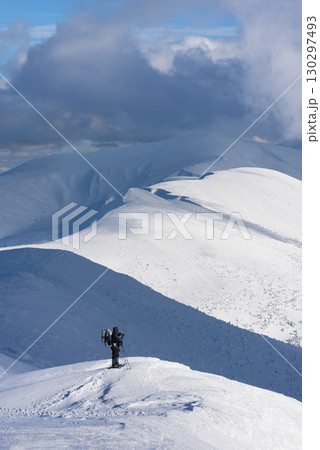 Hiker Standing on Snowy Mountain Ridge in Winter 130297493