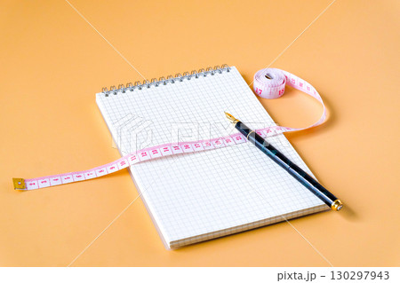 Measuring tape on notebook page on color background. 130297943