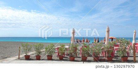 Beach umbrellas and sun loungers by sea Lacoste brand. Summer, vacation in Liguria, Italy. Background for text. 130297970