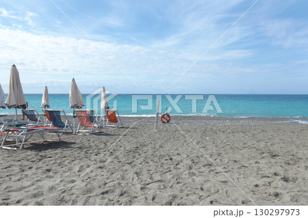 Beach umbrellas and sun loungers by sea Lacoste brand. Summer, vacation in Liguria, Italy. Background for text. 130297973