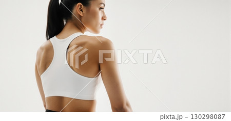 Woman in white sports bra posing for activewear and fitness fashion concept 130298087