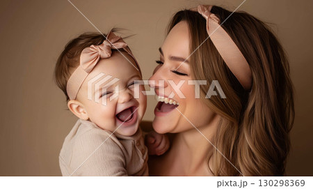 Mother and baby share joyful moment, both smiling and wearing matching headbands, showcasing love and happiness 130298369