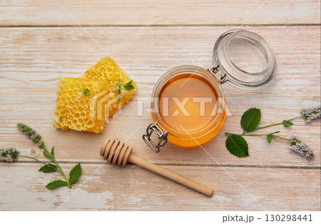 Honeycomb, jar of honey and wooden honey dipper on rustic table Honeycomb, jar of honey and wooden honey dipper on rustic table 130298441