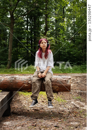 Young relaxed girl listening music with headphones in forest 130298447