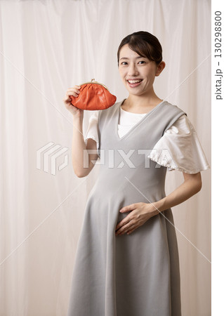 赤い財布を持って微笑む妊娠8ヶ月の女性 赤い財布を持って微笑む妊娠8ヶ月の女性 130298800