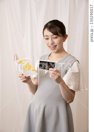 母子手帳とエコー写真を見る妊婦の女性 母子手帳とエコー写真を見る妊婦の女性 130298817
