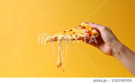 チーズが伸びるピザを持ち上げた黄色背景の写真 130299509