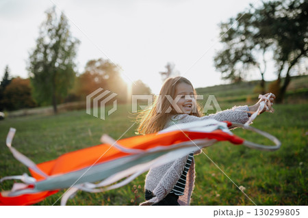 Girl playing with a rainbow hand kite in autumn nature at sunset. Girl playing with a rainbow hand kite in autumn nature at sunset. 130299805