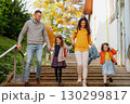 Sisters and parents jumping down the stairs in park during warm autumn day. 130299817
