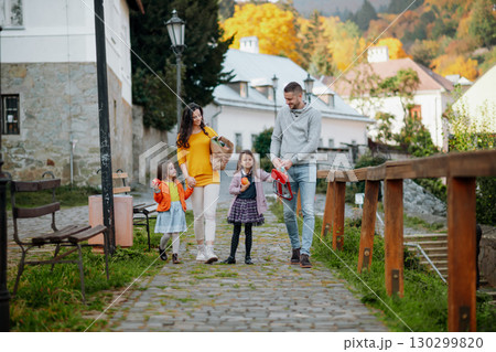 Sisters and parents walking in park during warm autumn day. 130299820