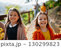 Sisters with parents in the background walking in park during warm autumn day. 130299823