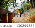 Sisters and parents walking in park during warm autumn day. 130299824