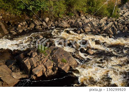 A Beautiful Serene River Gracefully Flowing Over Rocky Terrain in Natures Stunning Splendor 130299920