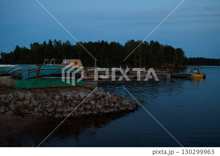 Experience a beautiful, scenic evening at the tranquil lake dock, complete with boats 130299963
