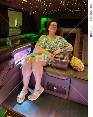 Woman sitting in luxury van with glowing ceiling lights. Relaxation, leisure and premium lifestyle in modern travel interior. Woman sitting in luxury van with glowing ceiling lights. Relaxation, leisure and premium lifestyle in modern travel interior. 130300165