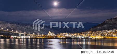 Panorama of the Norwegian city of Tromso on a winter evening during the Christmas season. The bridge over the fjord and houses are illuminated by city lights Panorama of the Norwegian city of Tromso on a winter evening during the Christmas season. The bridge over the fjord and houses are illuminated by city lights 130301236